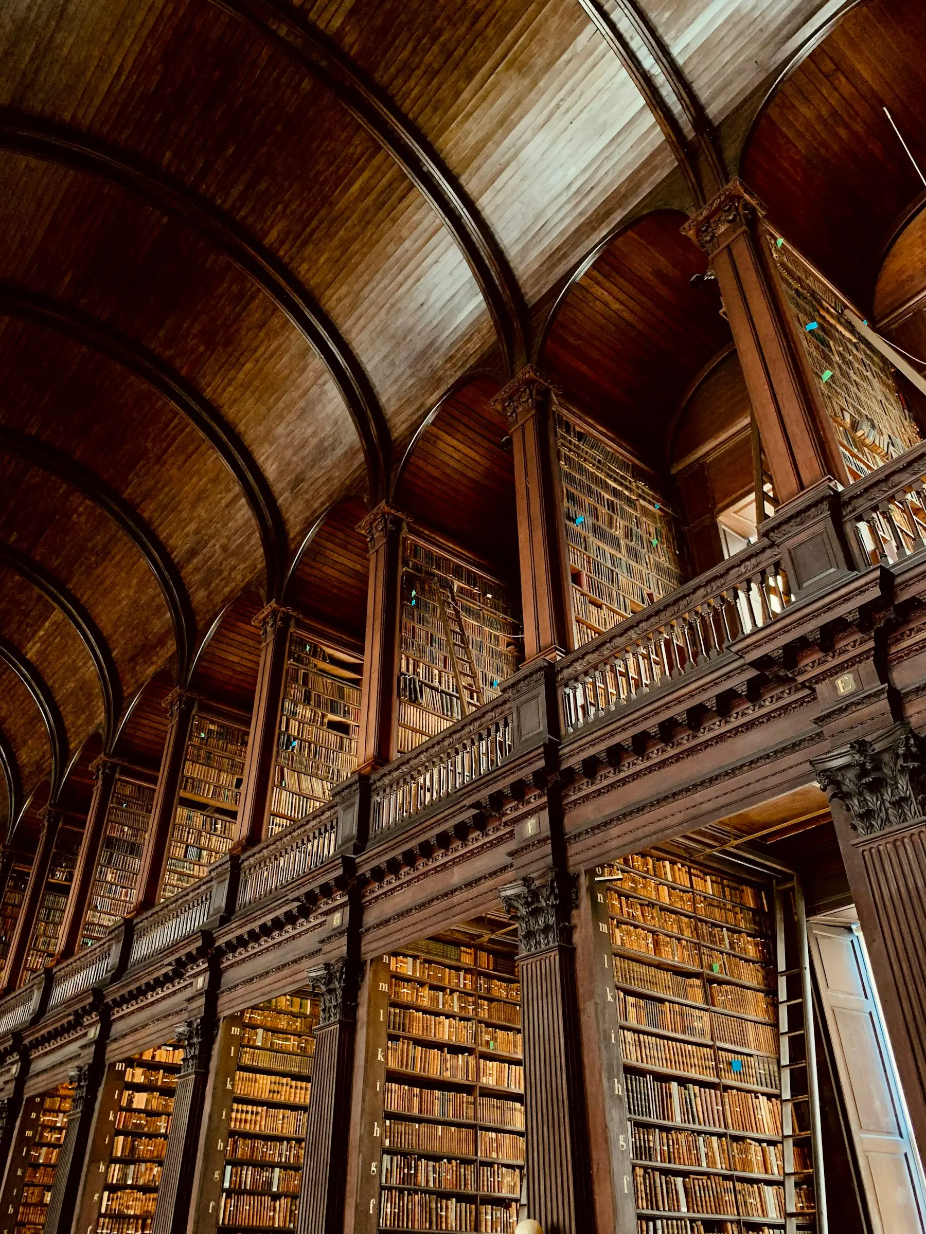 Sala di una biblioteca storica con ballatoi in legno e scaffali colmi di libri antichi