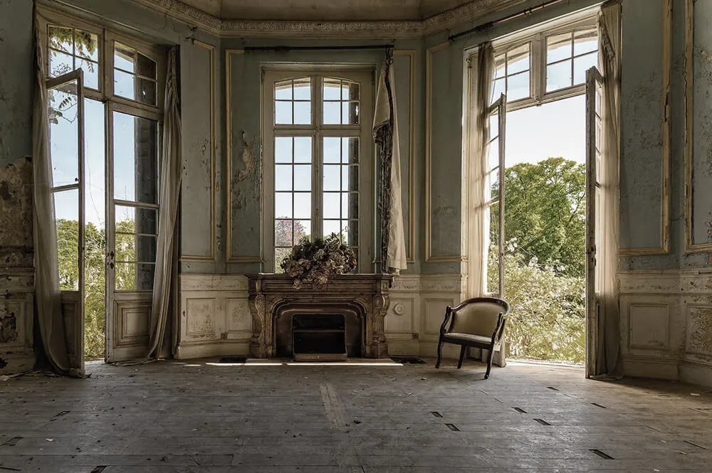 Salone di una villa d'epoca con camino e porte finestre aperte sul giardino